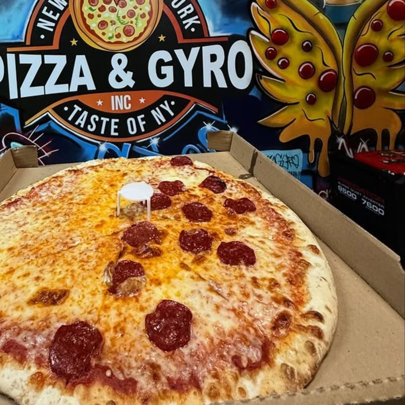 A large pepperoni pizza in a box, with the NY Pizza & Gyro logo in the background.